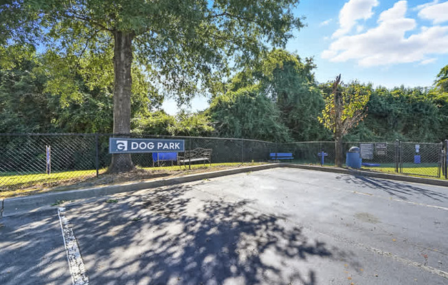 A sign for Dog Park is seen in front of a fence.