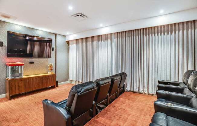 A home theater with black leather chairs and a wooden entertainment center.