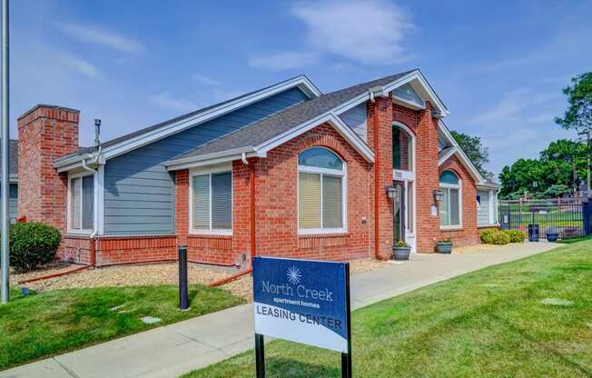 a red brick home with a blue sign in front of it