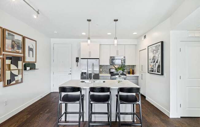 A kitchen with a white table and black chairs.