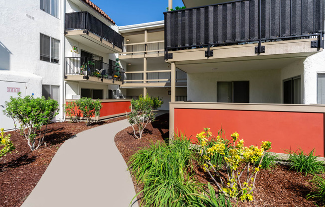 an exterior view of an apartment building with a walkway and plants