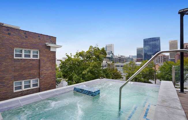 A hot tub on a balcony with a city skyline in the background.