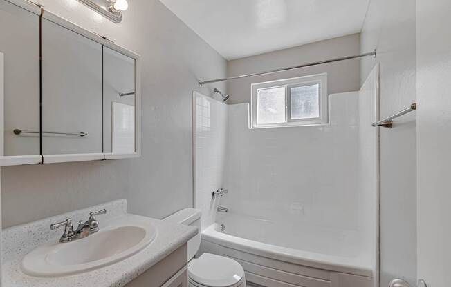 A white bathroom with a sink, toilet, and bathtub.