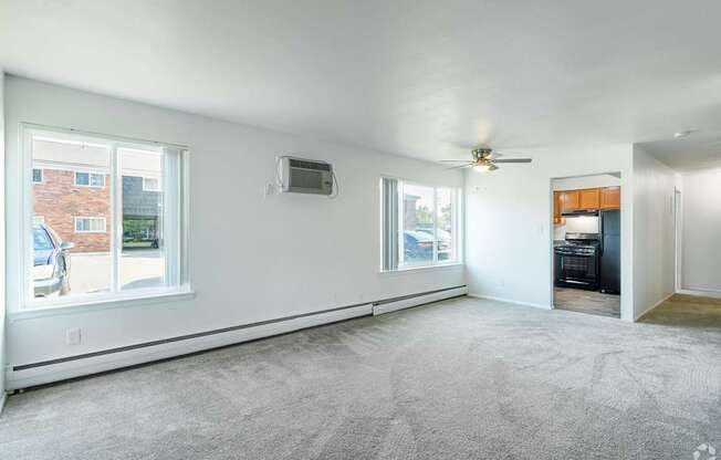 an empty living room with large windows and a ceiling fan