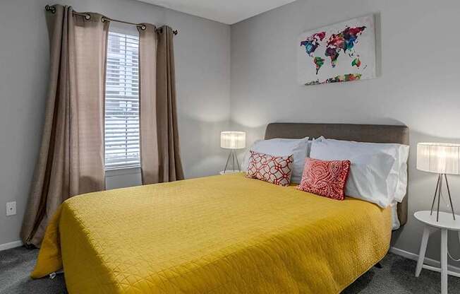 A bedroom with a yellow bedspread and a world map artwork on the wall.