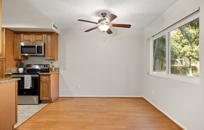 an empty kitchen with a ceiling fan and a window