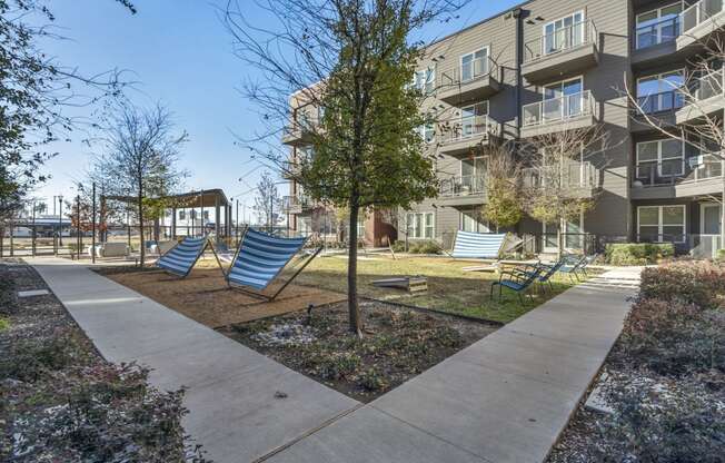 an empty playground with chairs in front of an apartment building