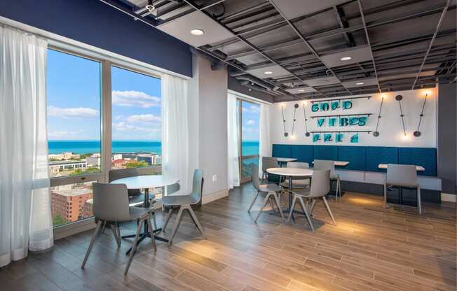 a room with tables and chairs and a view of the ocean