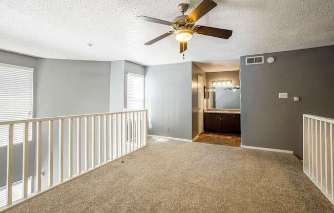 A room with a ceiling fan and carpeted floor.