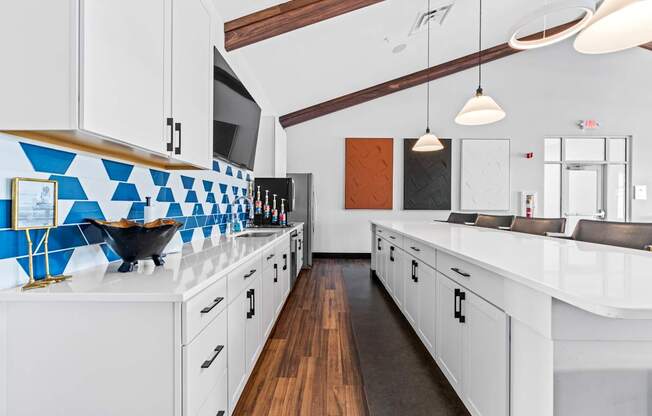 A kitchen with white cabinets and a blue tile backsplash.