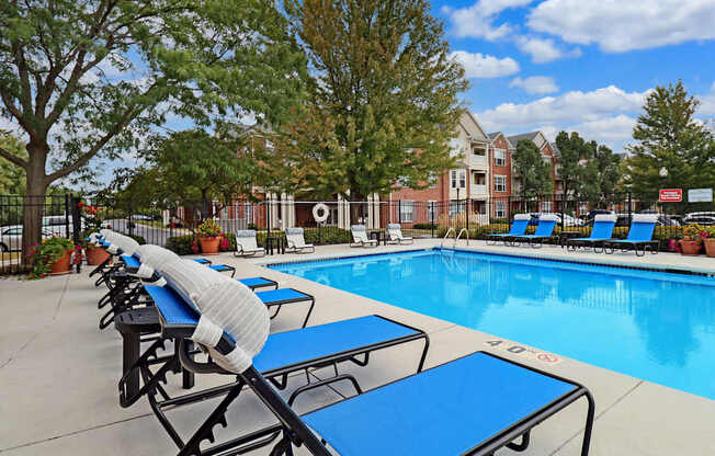 A poolside area with sun loungers and trees.