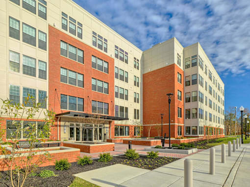 an exterior view of an apartment building with a sidewalk and courtyard at The Encore at Ingram Manor, Pikesville, MD