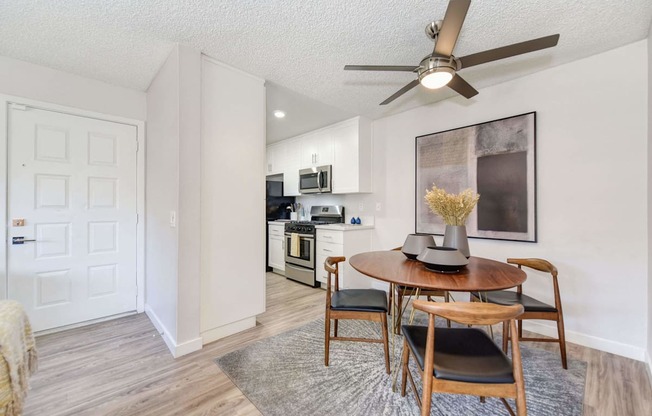 A dining room with a table set for two and a ceiling fan.