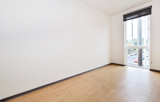 a bedroom with a large window and hardwood floors