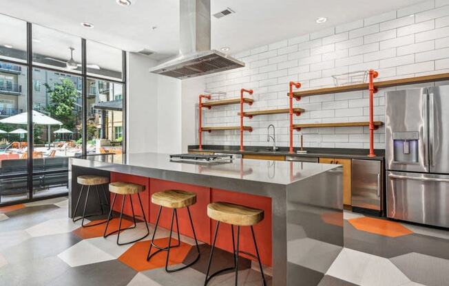 the kitchen has a large island with orange stools and stainless steel appliances at Link Apartments Innovation Quarter, Winston Salem, 27101