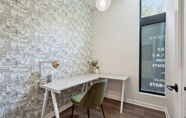 A white desk with a green chair in front of a wall with a mosaic of buildings.