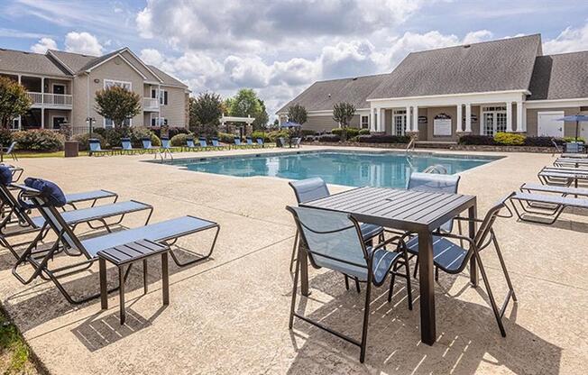 a swimming pool with tables and chairs around it at Bedford Parke Apartments, Warner Robins