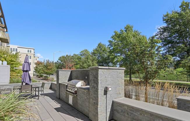 Patio area with a table and chairs and a stone wall at Park77 Apartments, Cambridge, MA
