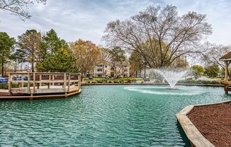 A fountain in the middle of a lake surrounded by trees.