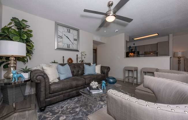 a living room with couches and chairs and a ceiling fan