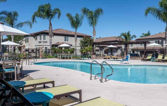 a gated swimming pool with chairs and umbrellas