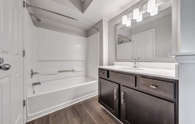 A bathroom with a white tub, sink, and mirror.