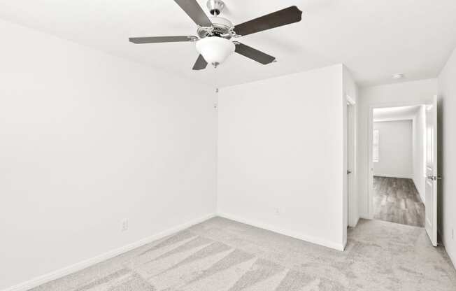 a bedroom with carpet floor, white walls and a ceiling fan