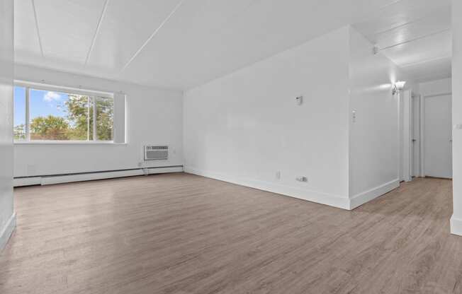 an empty living room with white walls and a window