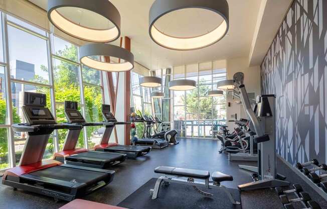 a gym with cardio equipment and windows in the lobby of a building