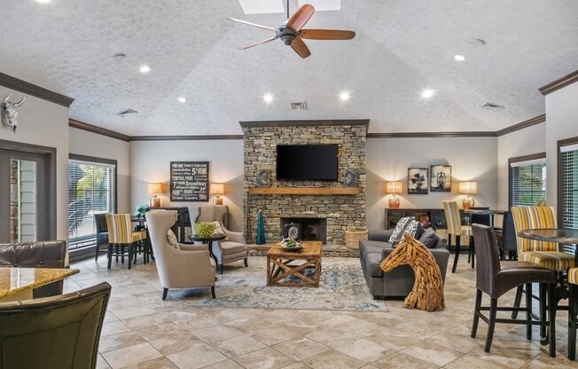 A living room with a stone fireplace and a flat screen TV at Ridge Crossings Apartments, Hoover