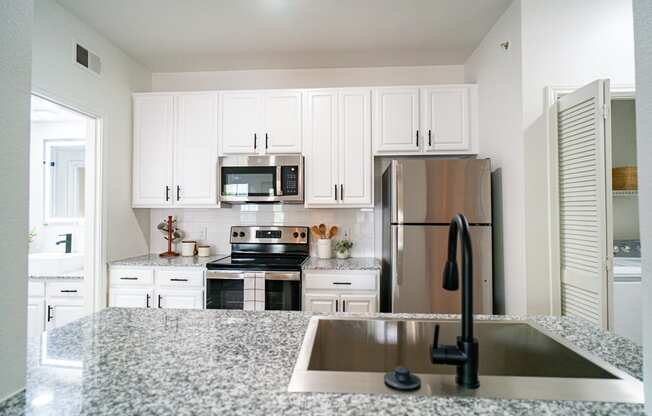 a white kitchen with granite counter tops and stainless steel appliances