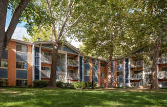 A tree in front of a building with balconies.