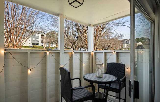 the screened in porch has a table and chairs and lights on it