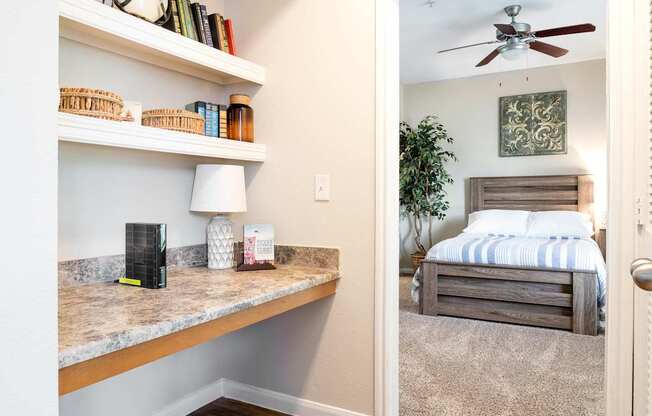 A room with a marble countertop and a bed in the background.