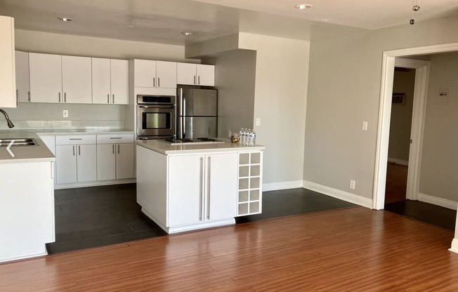 A kitchen with white cabinets and a wooden floor.