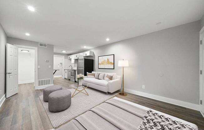 A living room with a white couch, a grey ottoman, and a rug.
