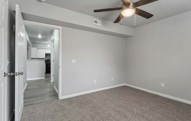 A room with a ceiling fan and a door leading to another room.