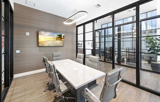 a meeting room with a table and chairs and a tv on the wall