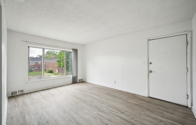A room with a white door and a window overlooking a street.