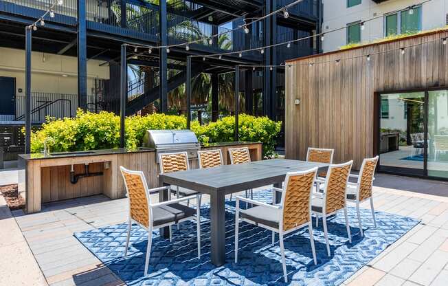 A table surrounded by chairs is on a patio.