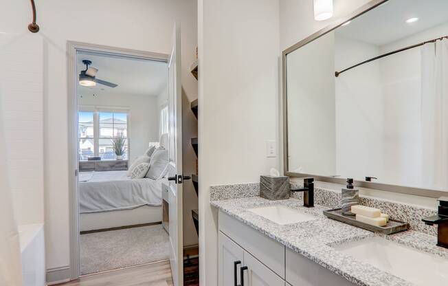 a bathroom with a sink and a mirror and a bedroom with a bed