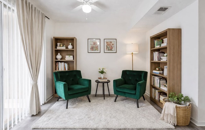 A living room with two green chairs and a white rug.