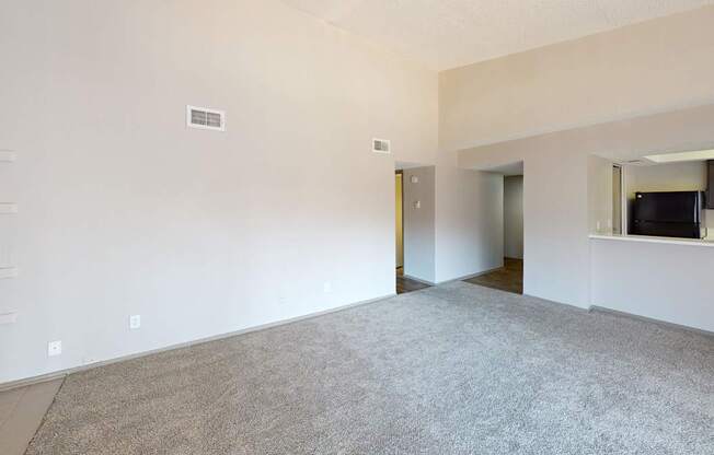 A large, empty room with a carpeted floor and white walls.