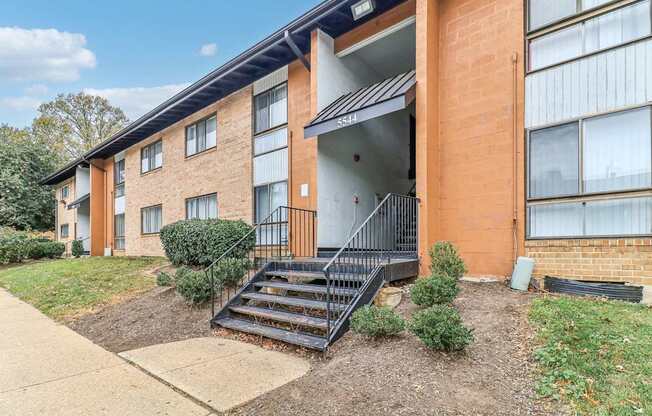 an apartment building with stairs and a sidewalk in front of it