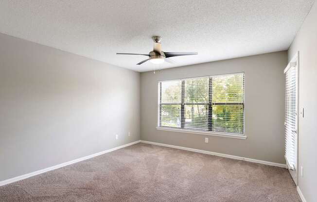 Model bedroom with windows, carpet, and ceiling fan at Fountains at Lee Vista in Orlando, Florida.