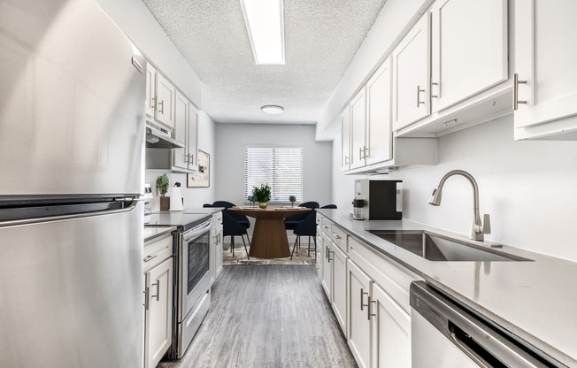 a large kitchen with white cabinets and stainless steel appliances and a dining room table