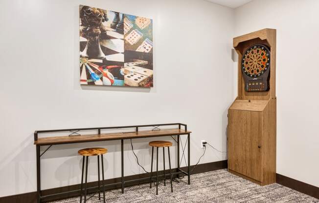a table with stools and a clock in a room with a painting on the wall