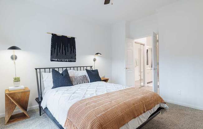 A bedroom with a bed, two lamps, and a ceiling fan.