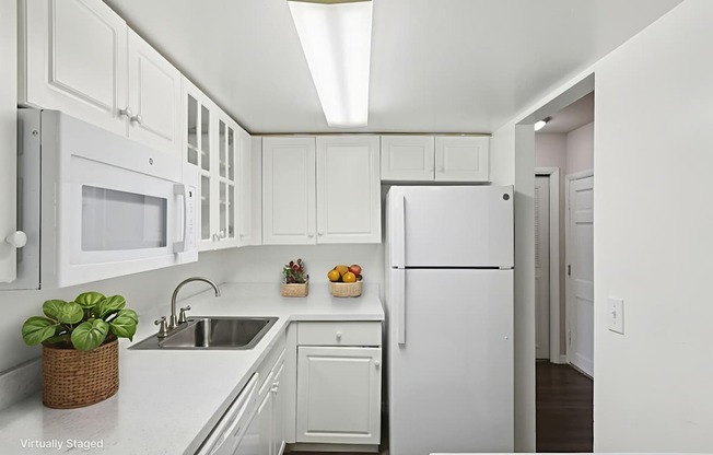 A white kitchen with a refrigerator, sink, and microwave.