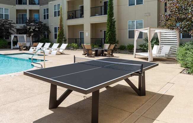 A black table tennis table is in the middle of a concrete patio.